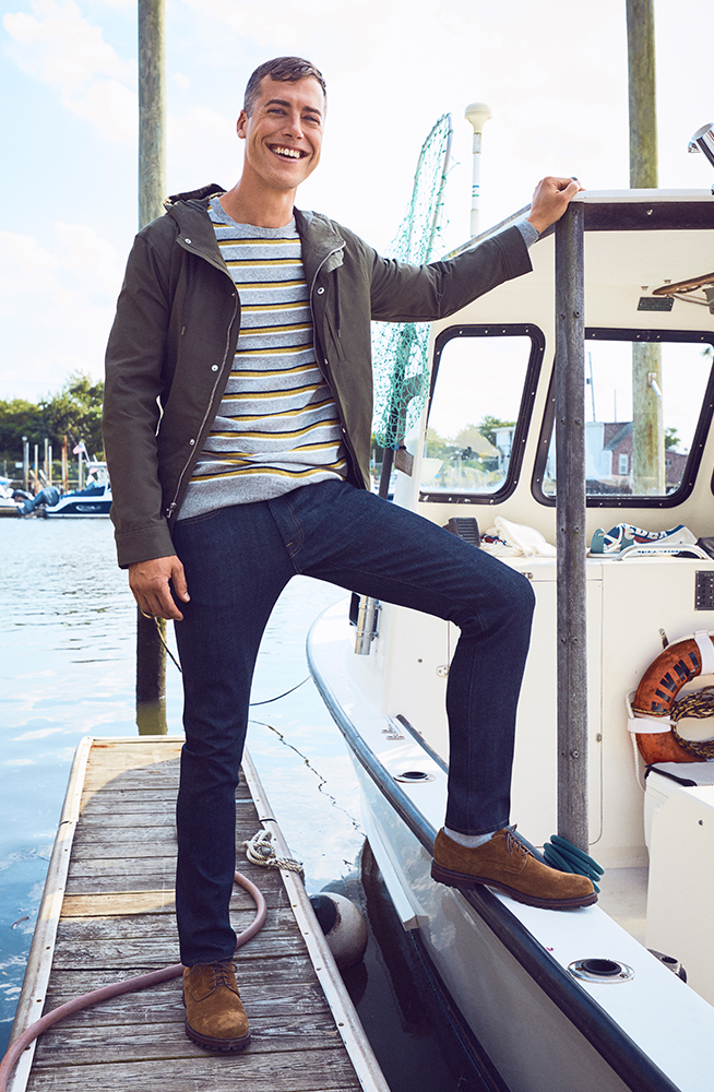 Brandon Sewall standing with one foot on his boat by the dock