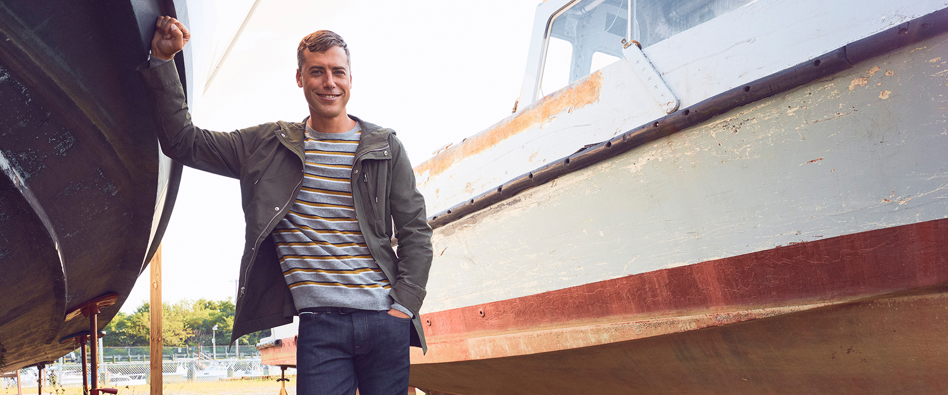 Brandon Sewall standing next to his boat wearing a green bonobos Jacket