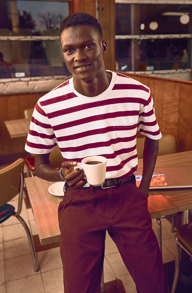Lual standing in a diner holding a cup of coffee